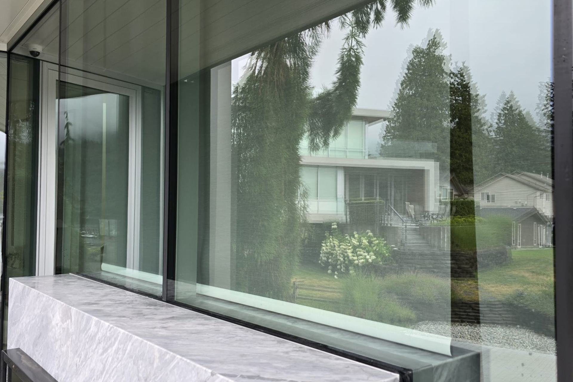 Clean, streak-free large windows reflecting trees and a modern home